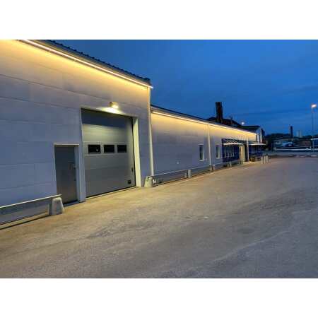 Europaljus - En vit byggnad med en LEDSTRIP 230V Highlum 15w/lpm 2700K IP65 lyser upp parkeringen på natten