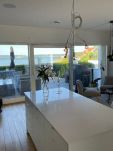 Europaljus - Ett vitt kök med utsikt över havet är upplyst av taklampa