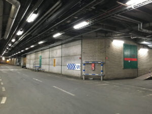 Europaljus - Ett parkeringsgarage med ledlysrör och en grön dörr upplyst av Europaljus.