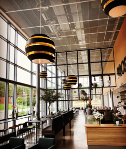 Europaljus - En restaurang med bord och stolar och ett stort fönster, badat i Europaljus.