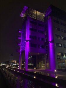 Europaljus - Byggnaden är upplyst i en bländande lila nyans på natten, vilket skapar en slående och levande syn.